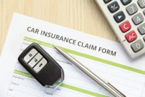 Top view of car insurance claim form with car key and calculator